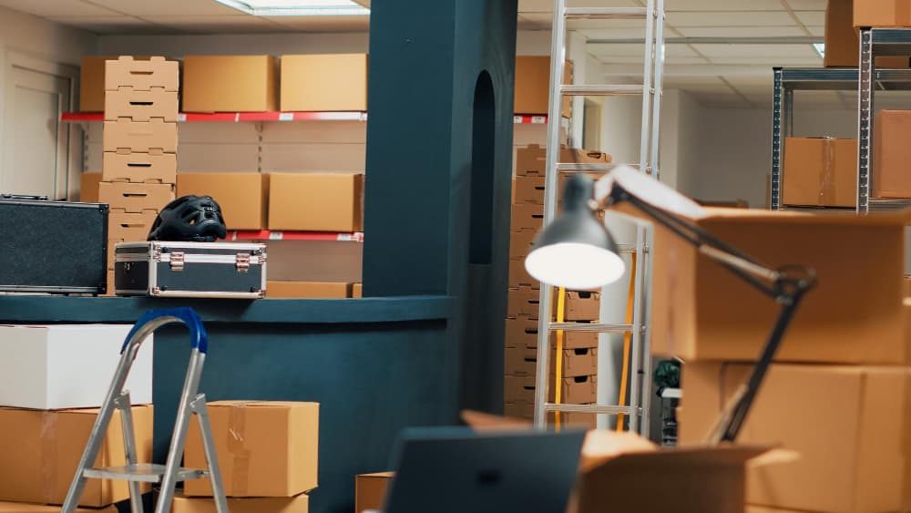 Dimly lit room filled with stacked cardboard boxes and shelves for office moving