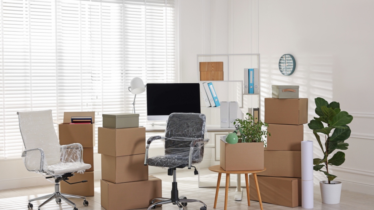 office space packed with plastic-wrapped chairs and stacks of cardboard boxes